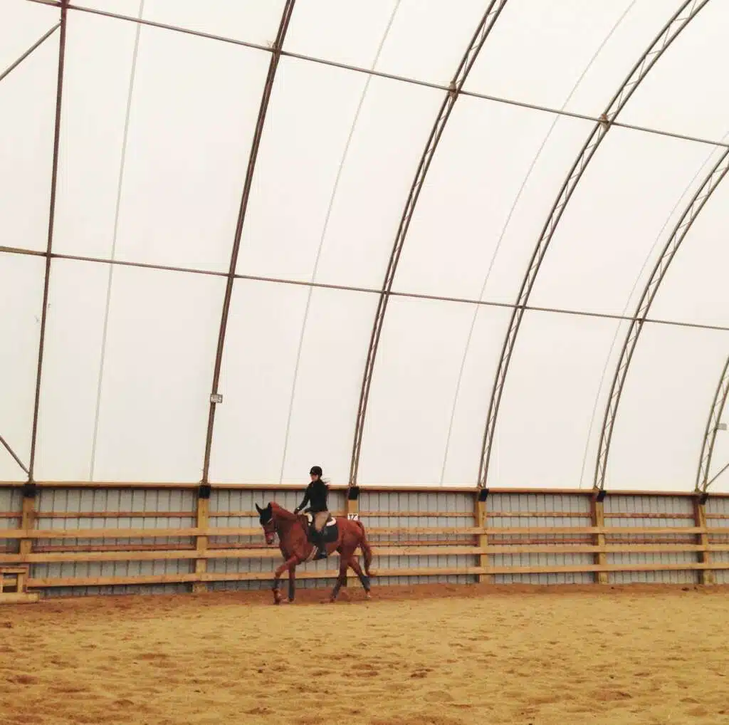 A woman riding a horse in a dome fabric covered structure