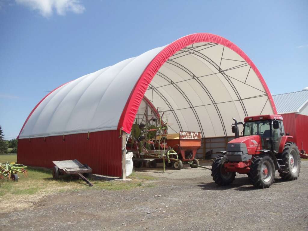 Dome fabric covered structure with a red tractor in front