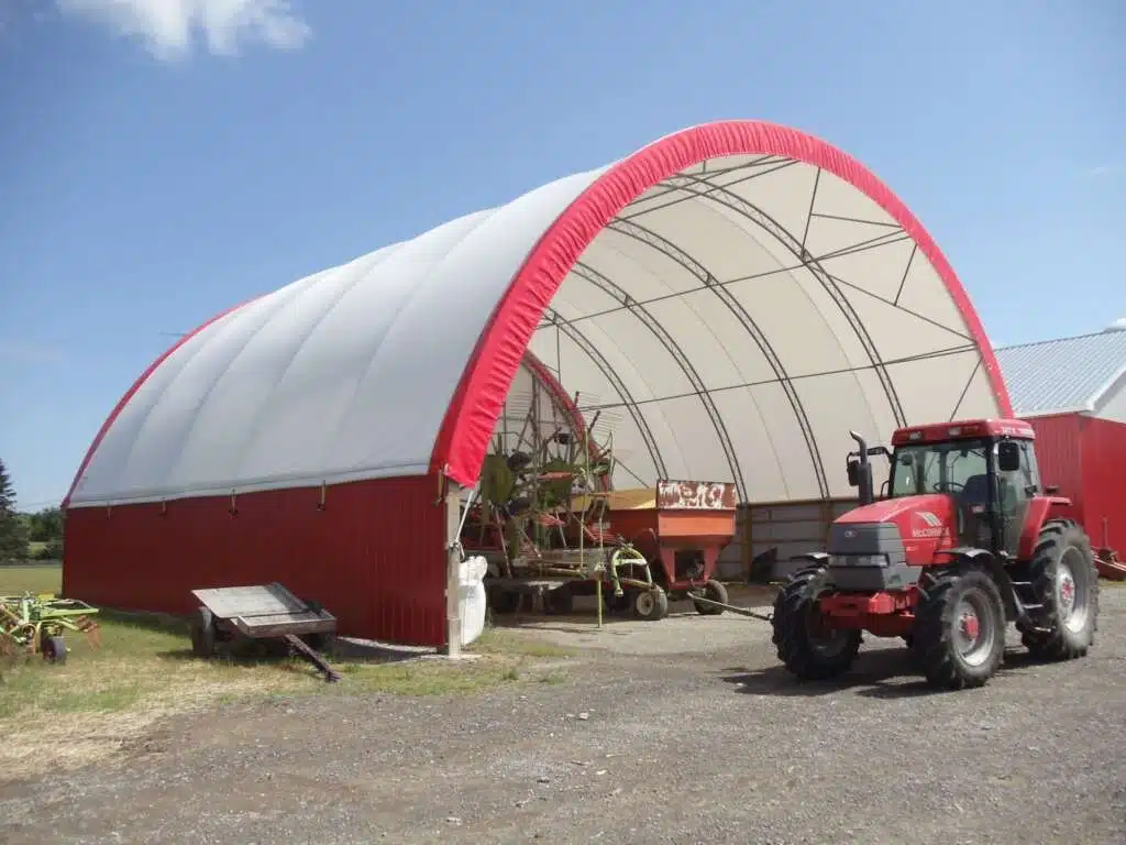 Dome fabric covered structure with a red tractor in front